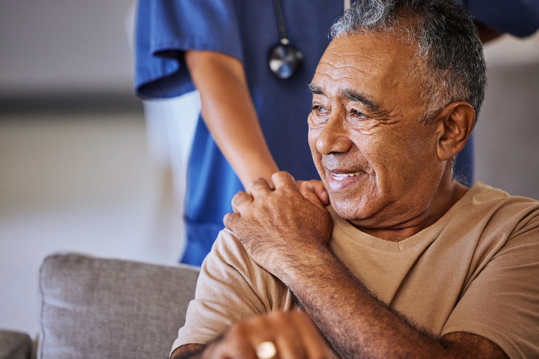 Nurse or doctor give man support during recovery or loss. Caregiver holding hand of her sad senior patient and showing kindness while doing a checkup at a retirement, old age home or hospital